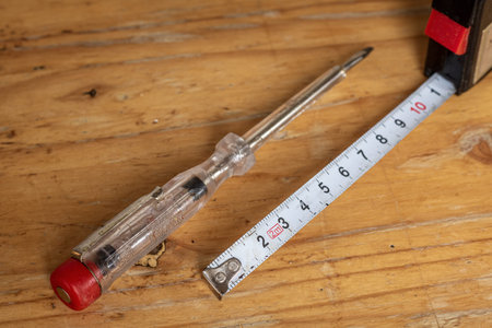 old voltage electric tester and white measuring tape, tools for do-it-yourselfers, are lying on a...
