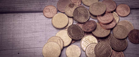 A collection of Eurocent coins in partly very used condition on a wooden surfaceの写真素材