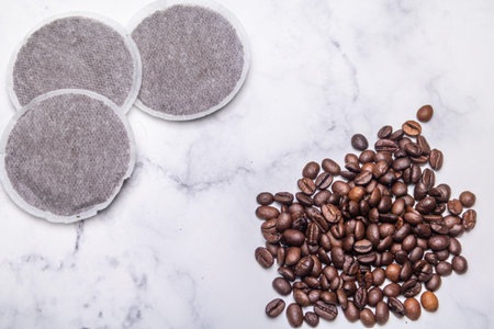 Top view of coffee pads and coffee beans on a marble surface as an example of various coffee raw...