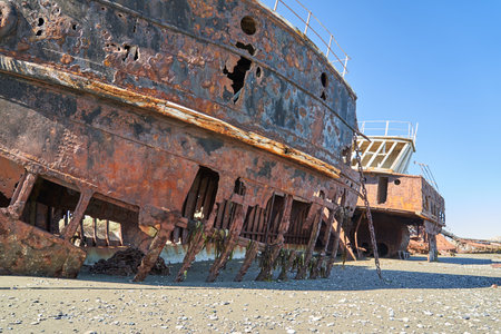 San Gregorio, Argentina-27.11.2018 old rusty and rotten ship wreck with holes in carcass, lying behind long gras on the beach of the coast line of the Strait of Magellan in Patagonia, abandoned placesの写真素材