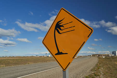 yellow and black road sign showing a palm tree leaning over in strong winds, warning of storm, can be found on tierra del fuego, Patagonia, south Americaの写真素材