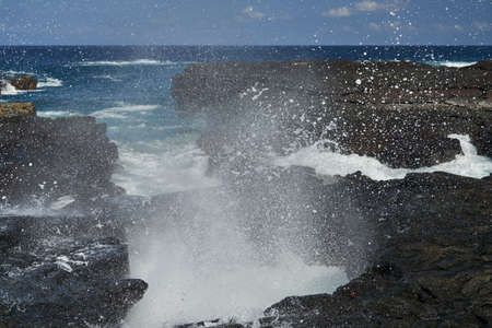 waves crushing over lava rocks on the shoreline of the galapagos islands, causing white and wild spray of sea water, Ecuador, South Americaの写真素材