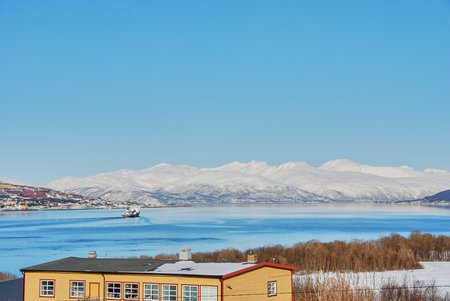 Fishing boat in the winter landscape of the port of Tromso in a fjord on the coastline of northern...