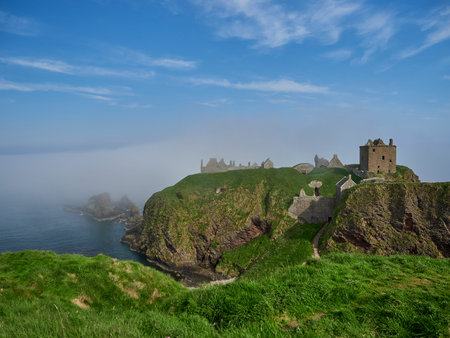 Dunnattor Castle, Scotland - 05 21 2018: Dunnottar Castle sitting high on a steep cliff of the atlantic ocean coastline of Scotland on a sunny day with yellow gorse.のeditorial素材