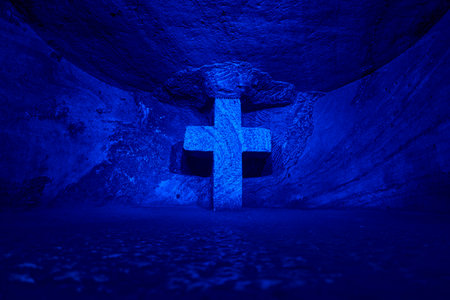 Zipaquira, Colombia - 04 12 2019: Stone cross at Catholic cathedral of Zipaquira is built into the tunnels of an underground salt mine and artfully illuminated in colorful light.のeditorial素材