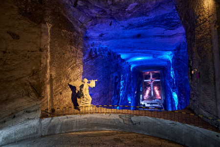 Zipaquira, Colombia - 04 12 2019: Angel sculpture and giant cross at Catholic cathedral of Zipaquira is built into the tunnels of an underground salt mine and artfully illuminated in colorful light.のeditorial素材