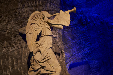 Zipaquira, Colombia - 04 12 2019: Angel sculpture and giant cross at Catholic cathedral of Zipaquira is built into the tunnels of an underground salt mine and artfully illuminated in colorful light.のeditorial素材