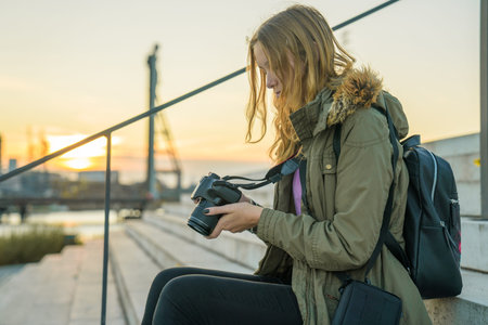 Young woman with a SLR is checking picture previews on the camera display