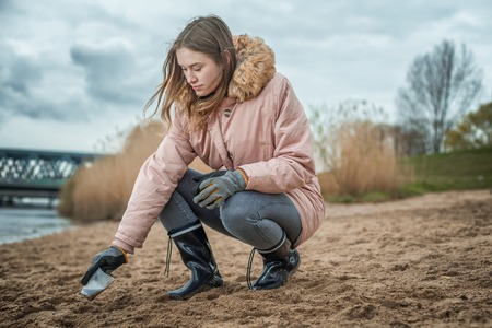 Young woman is cleaning the beach from platic waste by handの写真素材