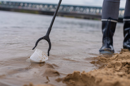 Close up collecting plastic garbage with a pair of pliers