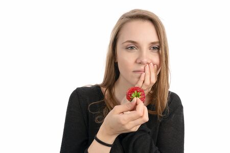 Young woman is pain sensitive when eating sweet strawberryの写真素材