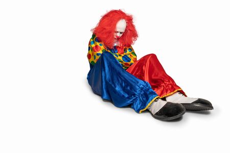sad clown is sitting on the floor looking downの写真素材