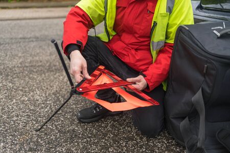 Closeup of a person tries to build a warning triangle on the streetの写真素材