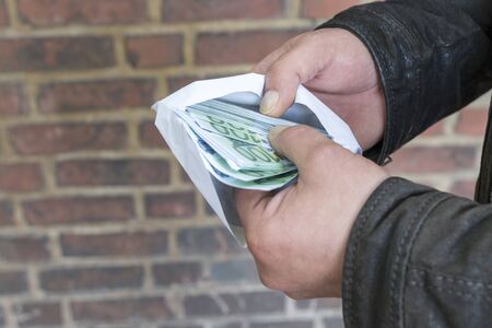 A man is counting money in an envelopeの写真素材