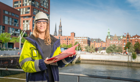 a female engineer holding a clipboard in front of city background