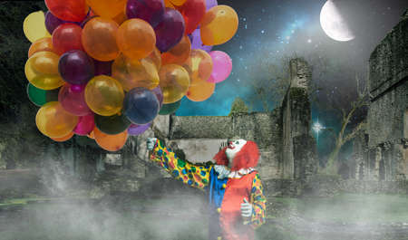 A happy clown is holding lots of balloons against a creepy backgroundの写真素材
