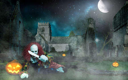 a horror halloween clown with a knife in front of an old castle at nightの写真素材