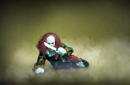 a scary clown with knife on an abstract backgroundの写真素材