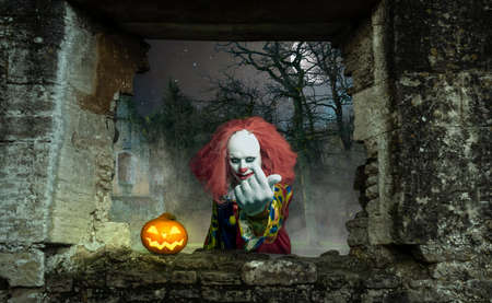 a scary clown with a pumpkin attracts the viewerの写真素材