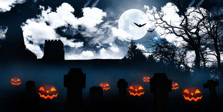 scary halloween pumpkins grinning on a cemetery at nightの写真素材