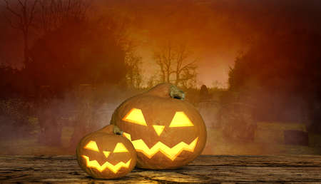 a scary halloween background with grinning pumpkins and tombstone in backgroundの写真素材