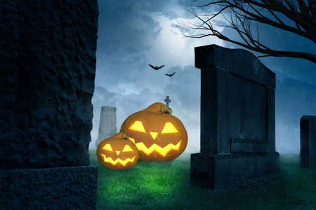 a creepy halloween background with grinning pumpkins on a cemeteryの写真素材