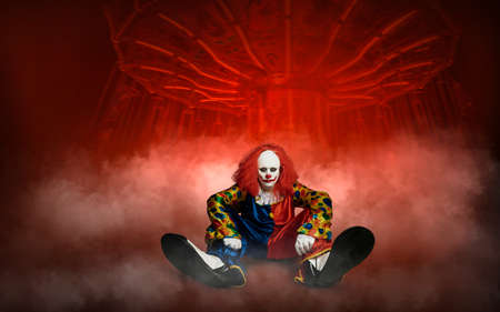 an expressionless clown against the abstract background of an amusement parkの写真素材