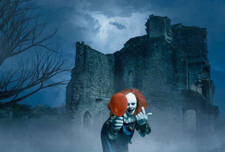 a crazy clown with a balloon in a gloomy scene of an old castleの写真素材