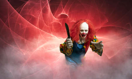 an evil clown with knife against abstract backgroundの写真素材