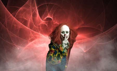 a creepy halloween clown in front of abstract background with gesture to mouthの写真素材