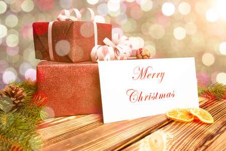 Christmas presents lie on a wooden table with a greeting card and abstract backgroundの写真素材
