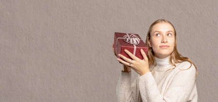 a close-up of a young woman holding a gift to her headの写真素材