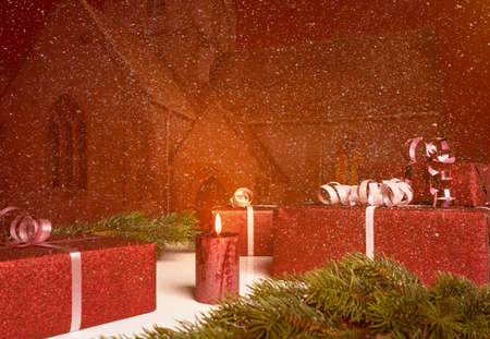 Christmas presents lie on a table in the background of an old church while it is snowingの写真素材