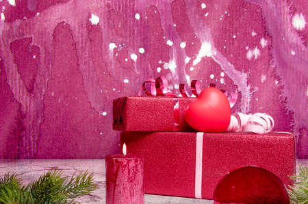 christmas presents and a candle with a heart in front of purple backgroundの写真素材