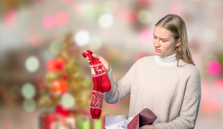 a disappointing Christmas present for a young woman in front of blurry christmas background