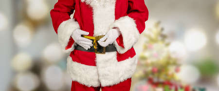 Santa Claus measures his stomach circumference with a tape measureの写真素材