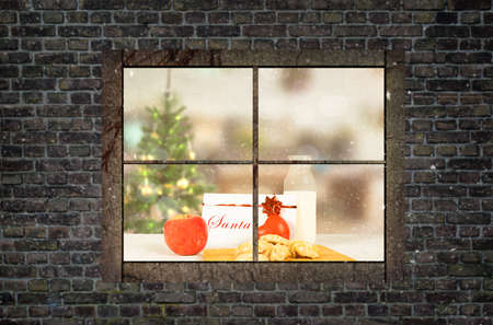 milk and biscuits prepared for the arrival of santa on a table look through a windowの写真素材