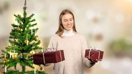 a woman in front of Christmas tree can not decide for a giftの写真素材