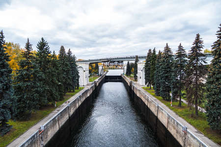 View of river canal and the bridge on it on the background of autumn landscape and cloudy skyの写真素材