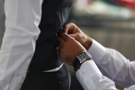 groom putting on cuff-links as he gets dressed in formal wear close up, close up of a hand man how wears white shirt and cufflink, business photoの写真素材