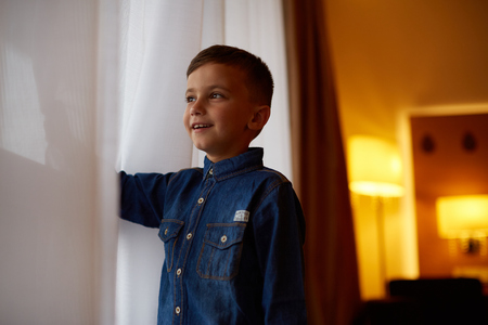 excited boy sitting near windowの写真素材