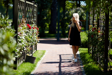 Beautiful sexy woman walk in the park summertime weather green trees road wear stylish short dress for party and walk glamour fashion clothes silk accessory bag outdoor street girl date perfect model.の写真素材