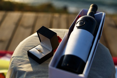 Marriage proposal setup with a ring in a wine glass with a rose and a bottle of wineの写真素材