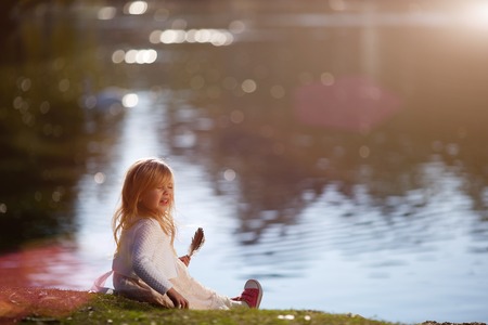 Little girl holding a bird feather and sneezes. Medical concept.の写真素材
