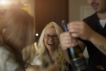 man opens champagne beautiful blonde laughsの写真素材