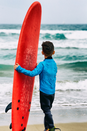 Boy on the beach with surfboardの写真素材