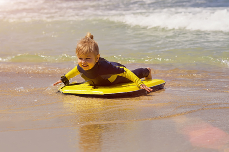 Young surfer girl with bodyboard walks along beach sea surfの写真素材