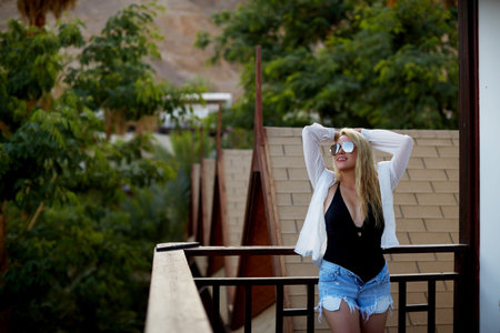 Beautiful blond model girl in a white vintage lace dress on the street in a summer dayの写真素材