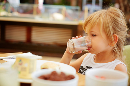 Little girl eating creme filled cookies while drinking a glass of milk.の写真素材
