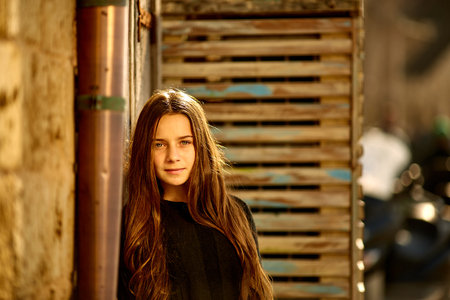 Portrait of beautiful unhappy with wind woman with fluttering red curly hair in summer clothes outdoors with city background.の写真素材